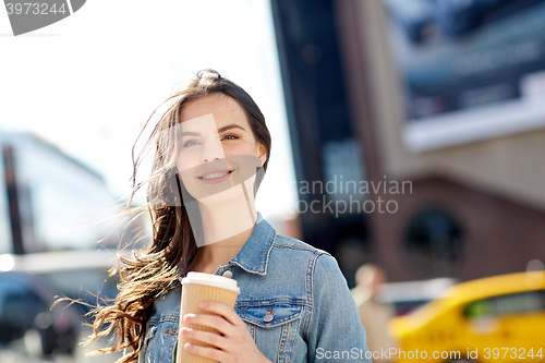 Image of happy young woman drinking coffee on city street