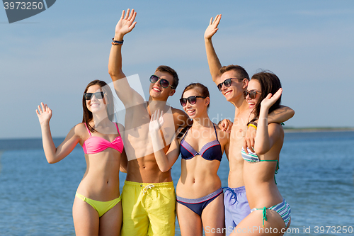 Image of smiling friends in sunglasses on summer beach