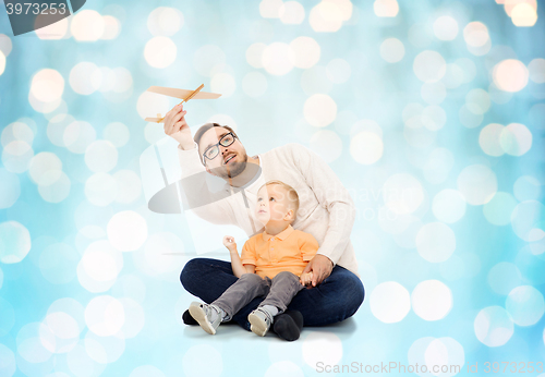 Image of father and little son playing with toy airplane