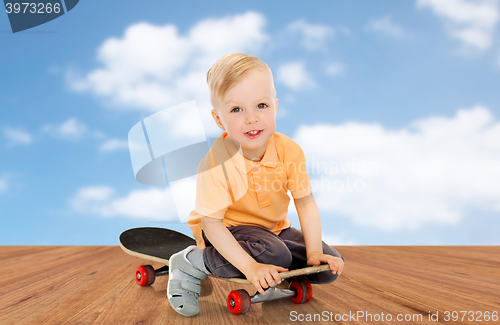 Image of happy little boy sitting on skateboard