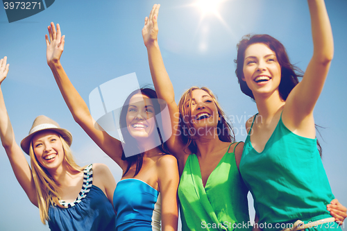 Image of girls walking on the beach and waivng hands