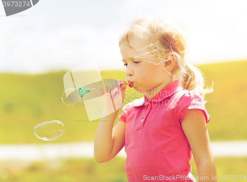 Image of little girl blowing soap bubbles outdoors