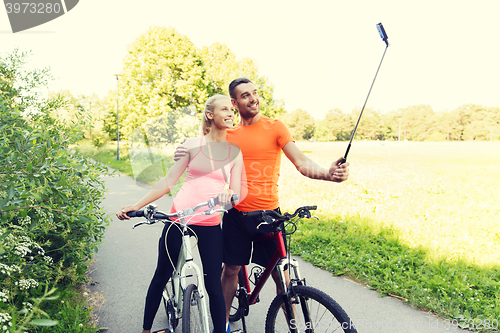 Image of couple with bicycle and smartphone selfie stick