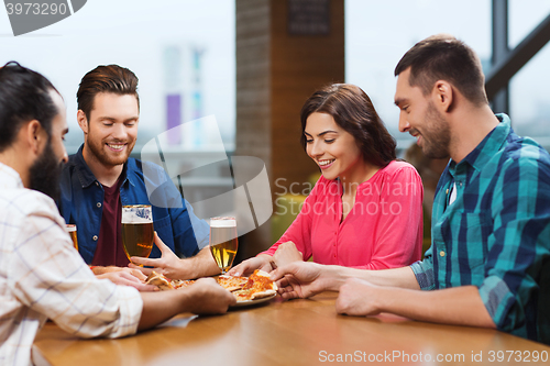 Image of friends eating pizza with beer at restaurant