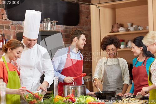 Image of happy friends and chef cook cooking in kitchen