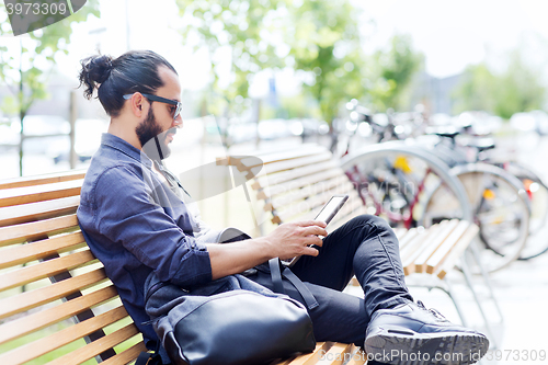 Image of man with tablet pc sitting on city street bench