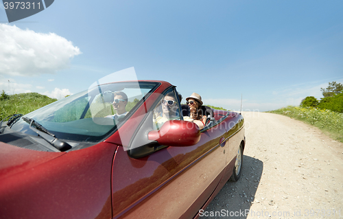 Image of happy friends driving in cabriolet car