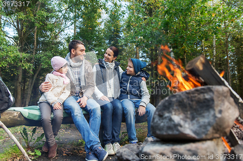 Image of happy family sitting on bench at camp fire