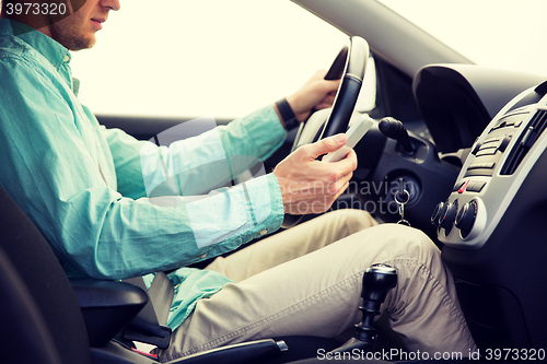 Image of close up of man with smartphone driving car