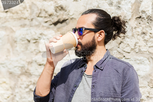 Image of man drinking coffee from paper cup on street