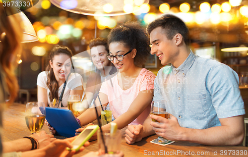 Image of happy friends with tablet pc and drinks at bar