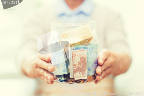 Image of close up of senior woman with money in glass jar