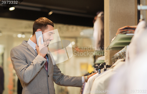 Image of happy man calling on smartphone at clothing store