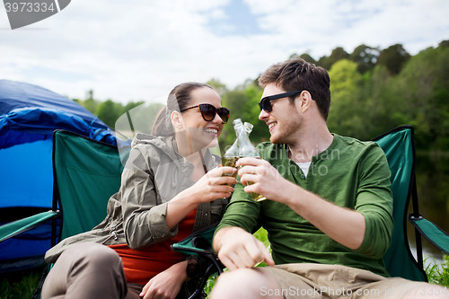 Image of happy couple clinking drinks at campsite tent