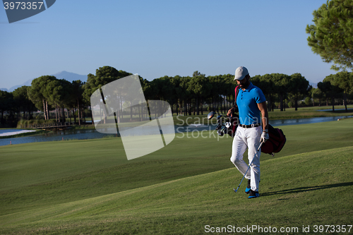 Image of golf player walking and carrying bag