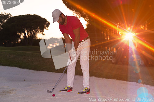 Image of golfer hitting a sand bunker shot on sunset