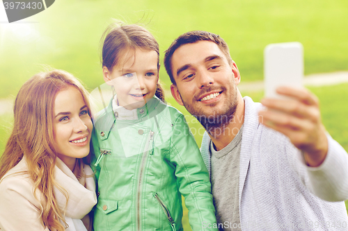 Image of happy family taking selfie by smartphone outdoors