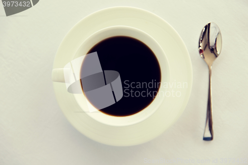 Image of cup of black coffee with spoon and saucer on table