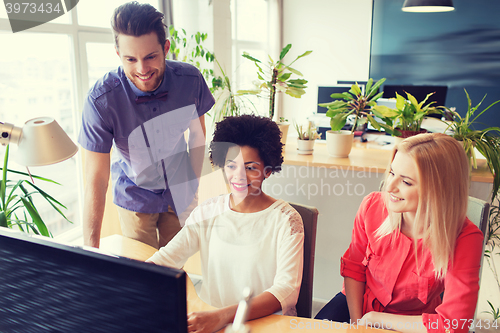 Image of happy creative team with computer in office