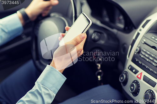 Image of close up of man hand with smartphone driving car