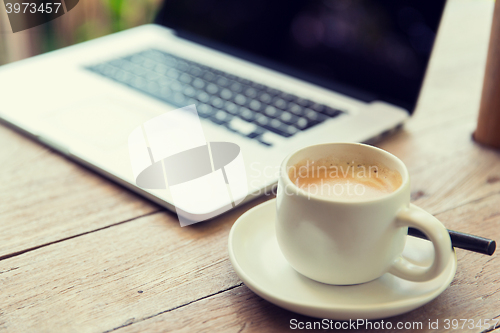 Image of close up of laptop and coffee cup on office table