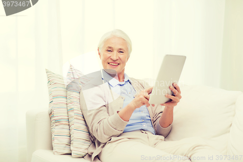 Image of happy senior woman with tablet pc at home