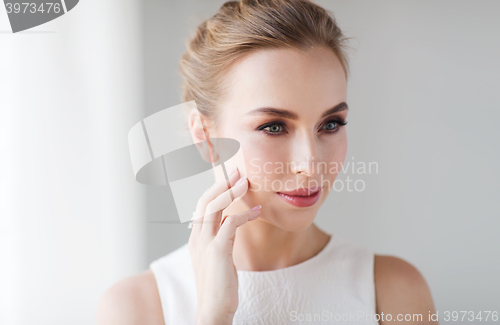 Image of beautiful woman in white dress touching her face