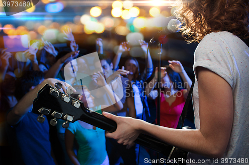 Image of female singer playing guitar over happy fans crowd