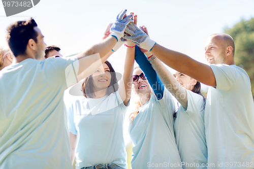 Image of group of volunteers making high five in park