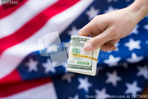 Image of close up of hand with money over american flag