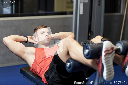 Image of young man making abdominal exercises in gym