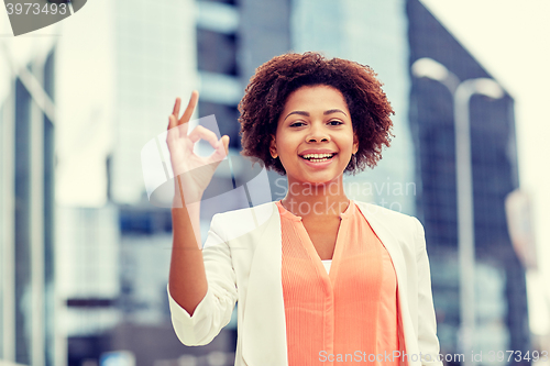 Image of happy african businesswoman showing ok in city