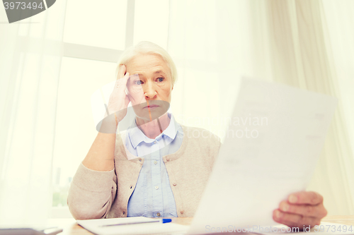 Image of senior woman with papers and calculator at home