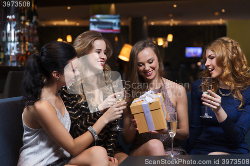 Image of happy women with champagne and gift at night club