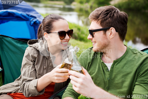 Image of happy couple clinking drinks at campsite tent