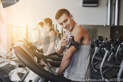 Image of man with smartphone exercising on treadmill in gym