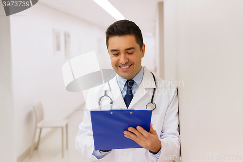 Image of happy doctor writing to clipboard at hospital