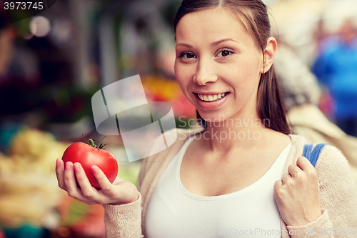 Image of happy woman holding tomato at street market