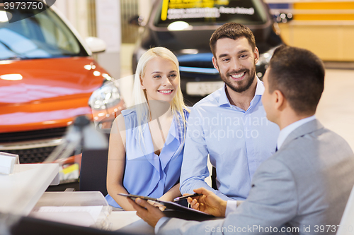 Image of happy couple with car dealer in auto show or salon