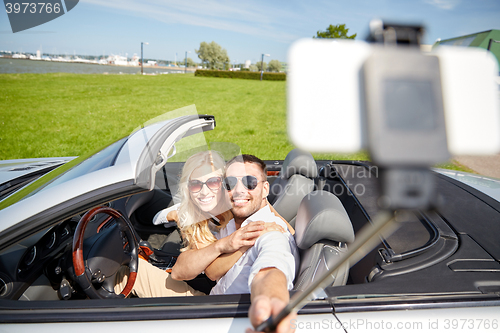 Image of happy couple in car taking selfie with smartphone