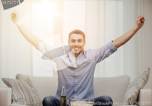 Image of smiling man watching sports at home