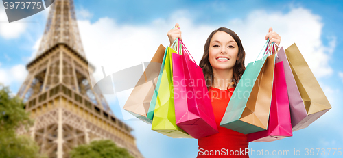 Image of happy woman with shopping bags over eiffel tower
