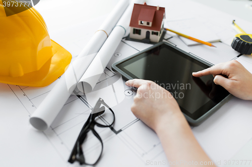 Image of close up of hand with blueprint and tablet pc