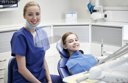 Image of happy female dentist with patient girl at clinic