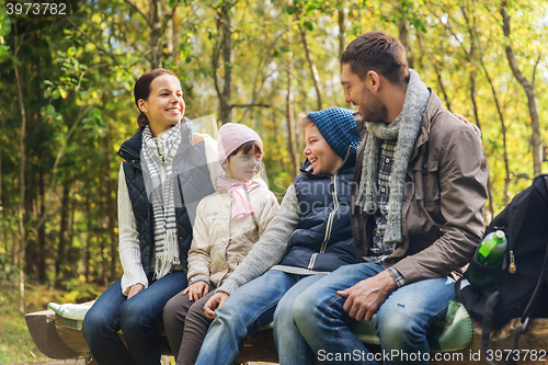 Image of happy family sitting on bench and talking at camp