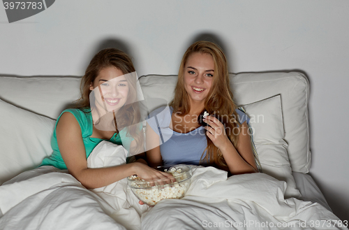 Image of happy friends with popcorn and watching tv at home