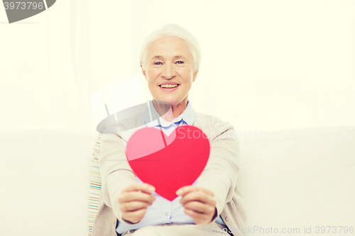 Image of happy smiling senior woman with red heart at home