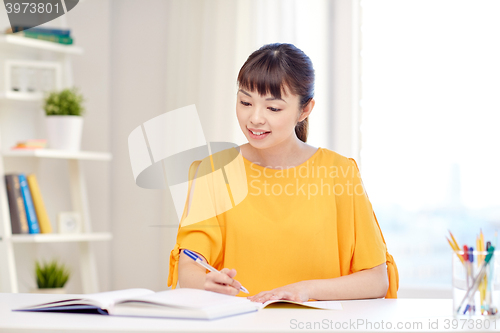 Image of happy asian young woman student learning at home