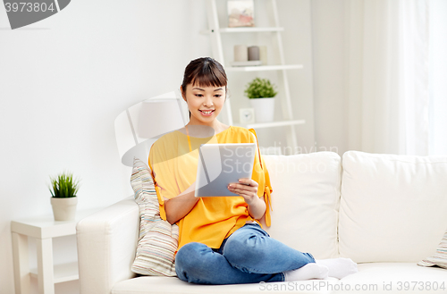 Image of happy young asian woman with tablet pc at home