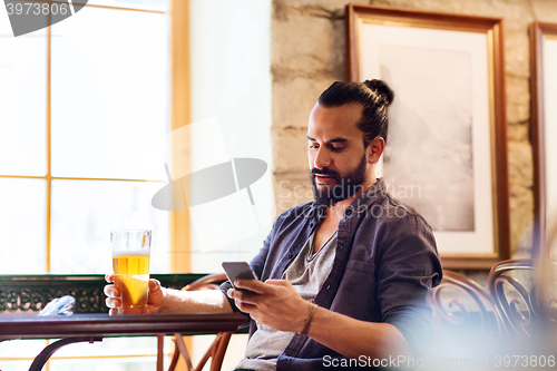 Image of man with smartphone drinking beer at bar or pub